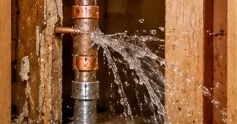 Burst pipe spraying water inside an open wall